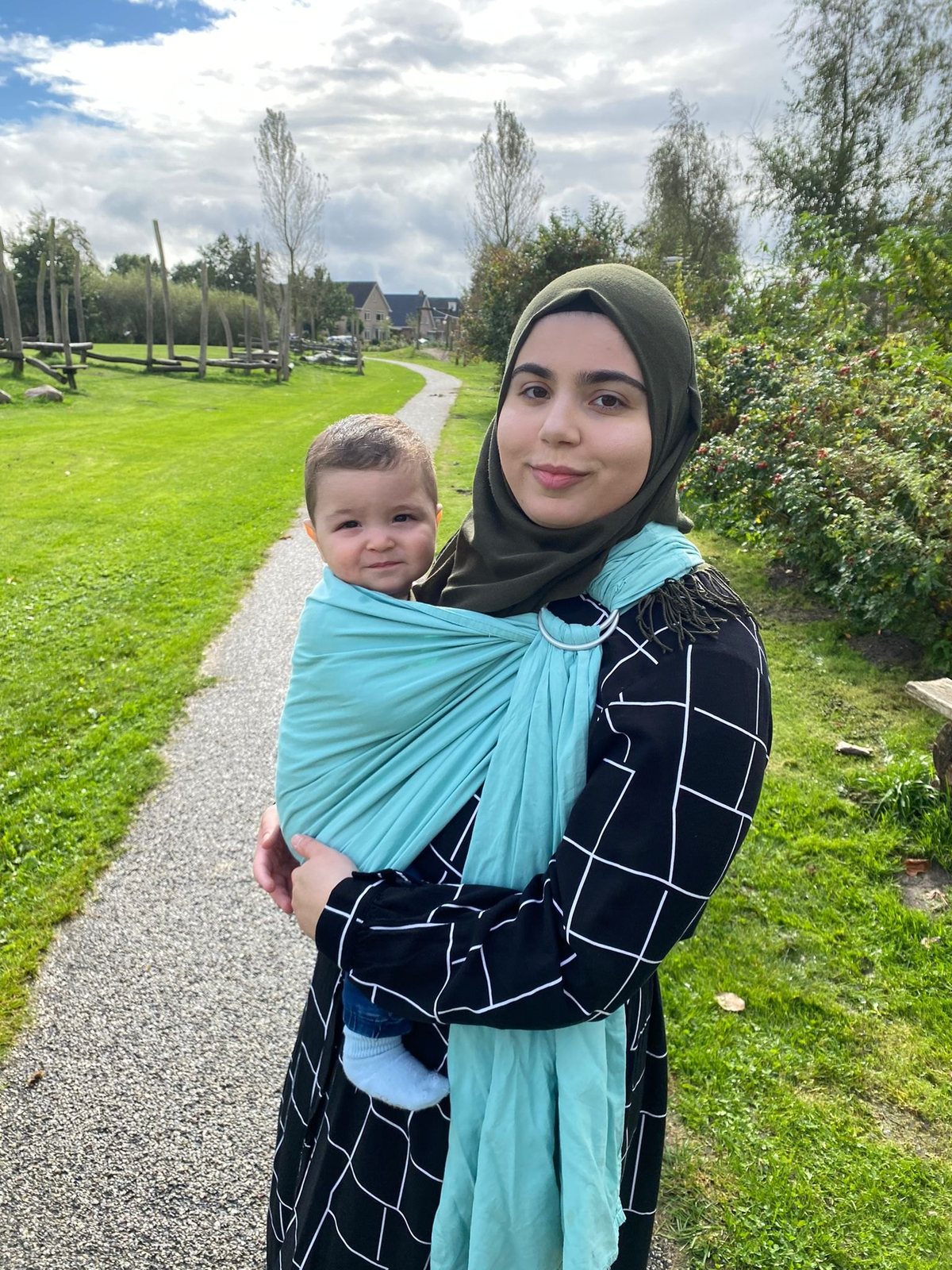 Feride draagt haar kindje in een turquoise ring sling op een wandelpad